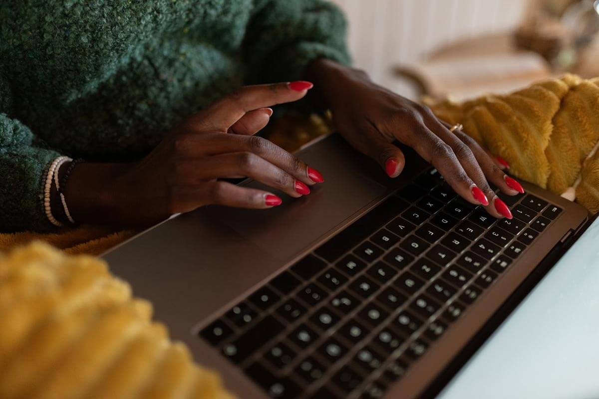 Woman typing on keyboard with red fingernails.